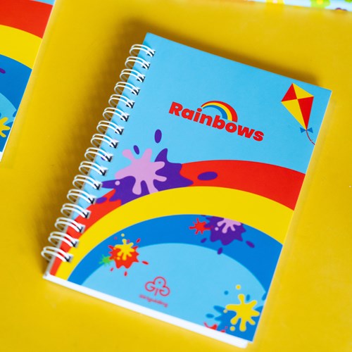 Rainbows notebook placed on vibrant yellow table 