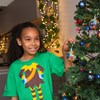 Child wearing elf t-shirt hanging Christmas  bauble on tree 