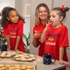 Adults and children decorating cookies while wearing naughty nice t-shirt 